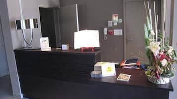 A reception desk with a computer, a telephone, and a floral arrangement.
