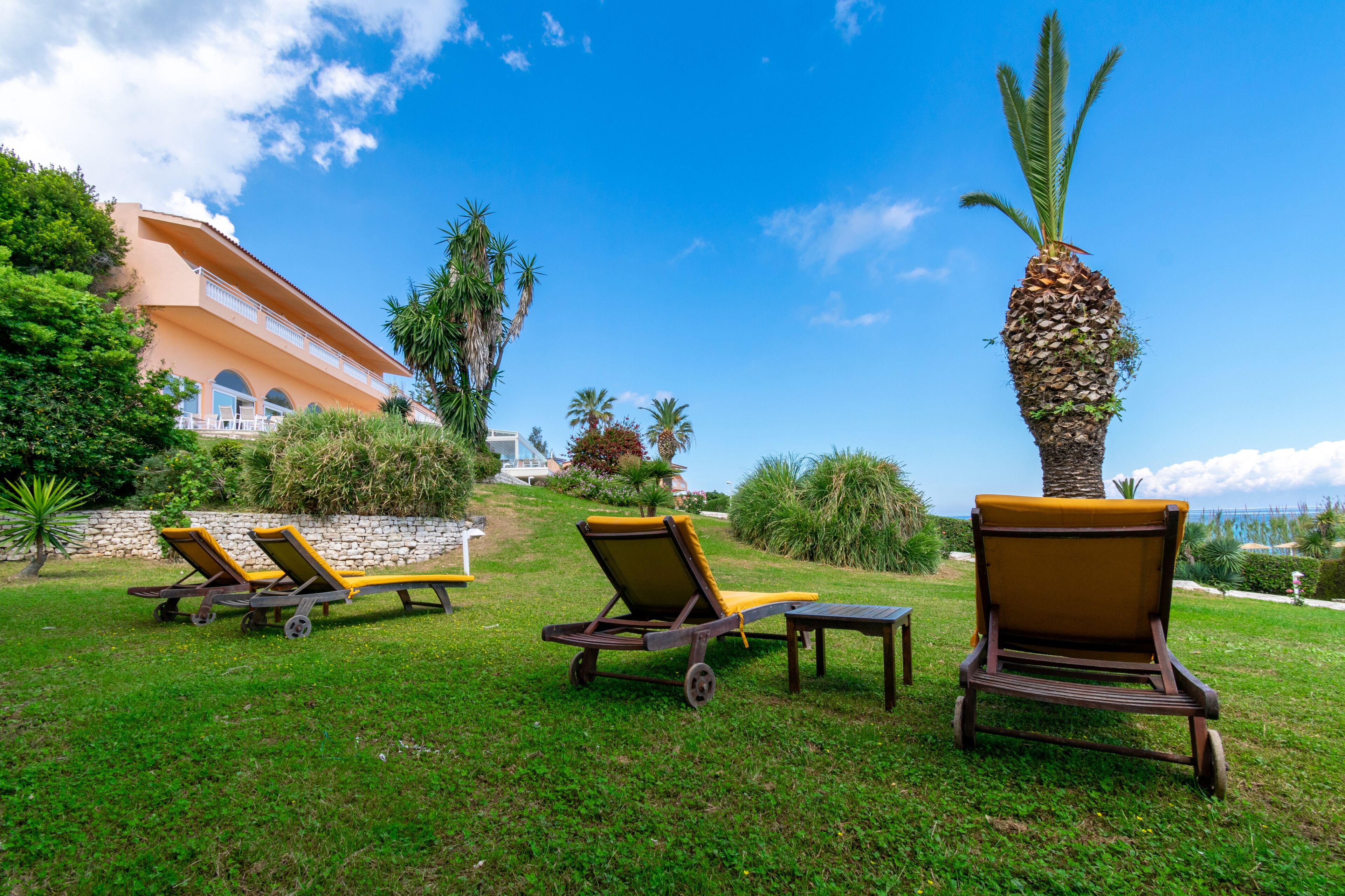 A resort with outdoor seating, a palm tree, and a building with balconies.