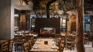 Un restaurant avec un mur en pierre, des tables et des chaises en bois.