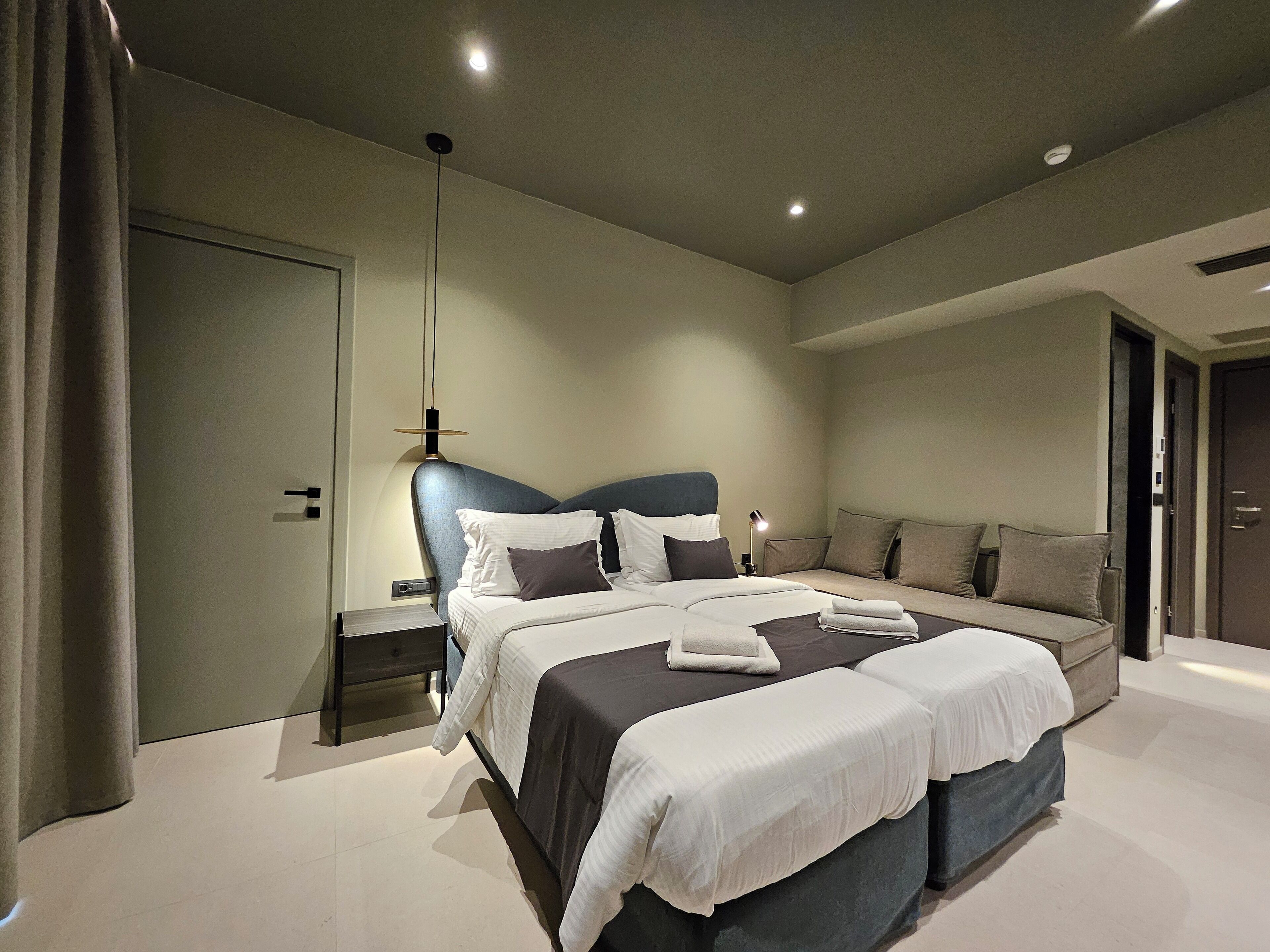 Une chambre moderne avec un grand lit, un canapé et une table de chevet.