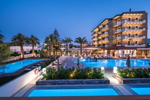 A hotel with multiple balconies, a swimming pool, and a landscaped garden area.