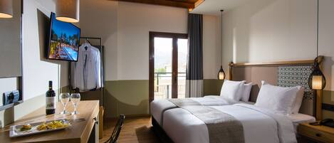 A hotel room with a bed, bedside table, TV, and a dining area with a table and chairs.