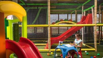 Zona de juegos con toboganes y una estructura cubierta con red.