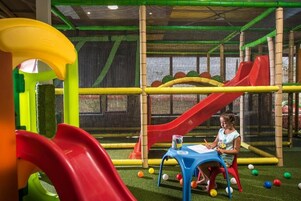 Zona de juegos con toboganes y una estructura cubierta con red.
