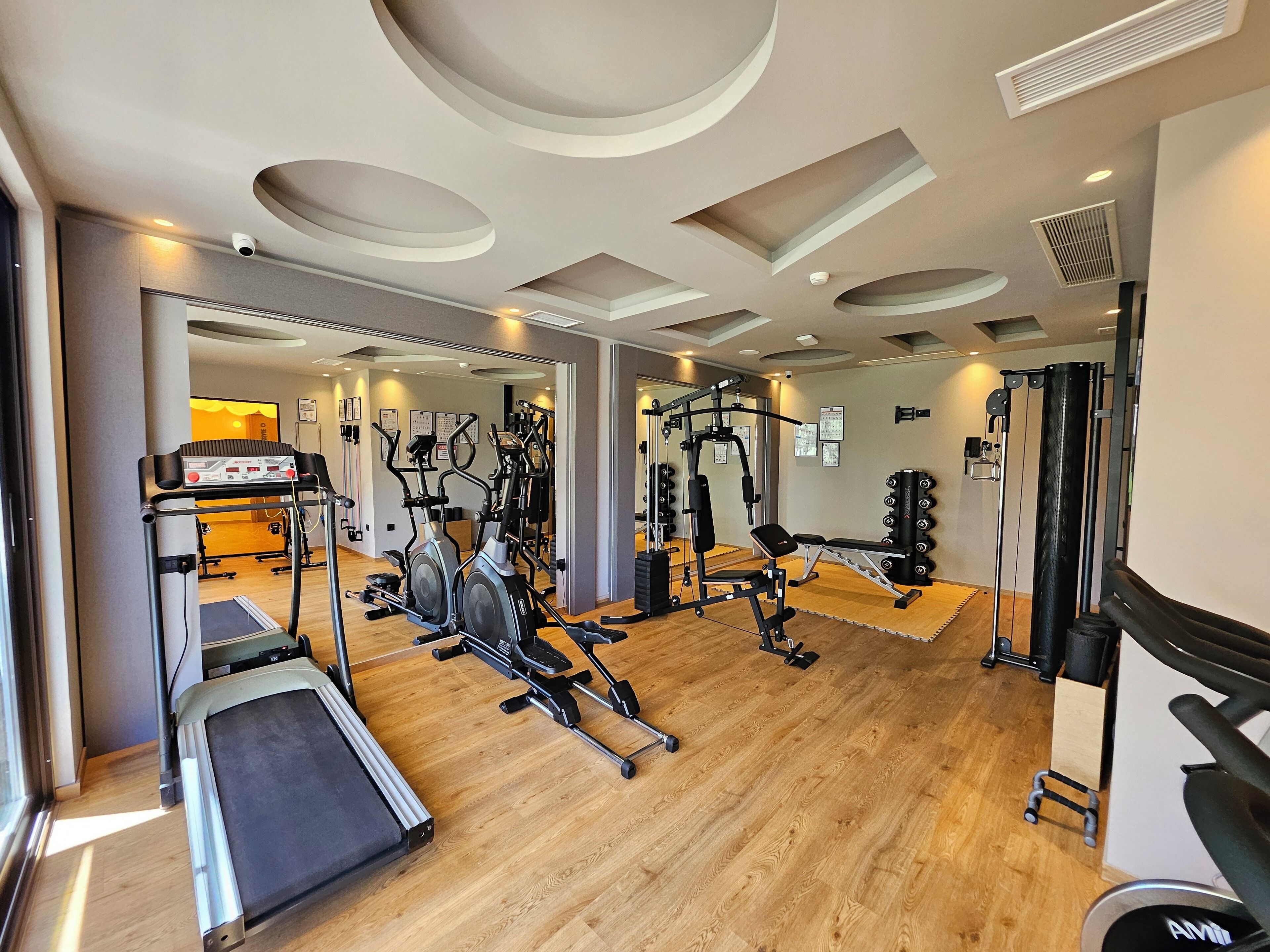Een moderne sportschool met cardioapparatuur, gewichten en een spiegelwand.