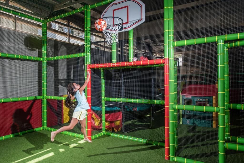 Un aro de baloncesto dentro de una zona de juegos delimitada por una red verde.