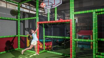 Un aro de baloncesto dentro de una zona de juegos delimitada por una red verde.