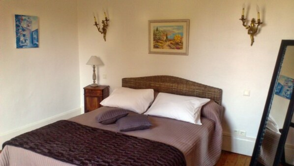 Un dormitorio con cama, almohadas, una lámpara y dos luces fijadas a la pared.