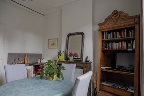 A dining area with a table, chairs, a mirror, a bookshelf, and a kitchen counter. - Aux Chambres du Roy (Roye)