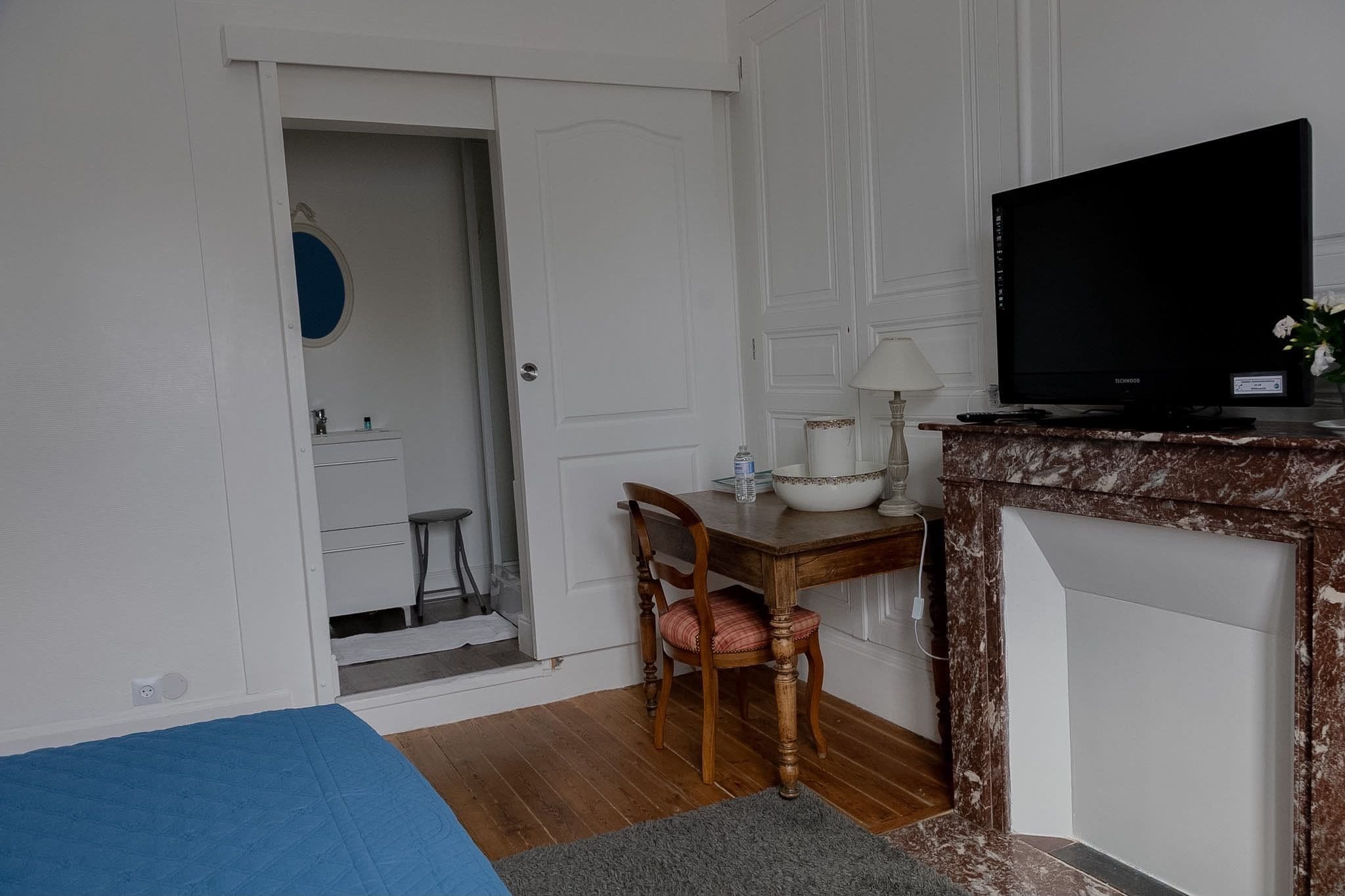 Ein Zimmer mit einem Bett, einem Schreibtisch mit Stuhl, einem Fernseher und einer Tür zu einem Badezimmer.