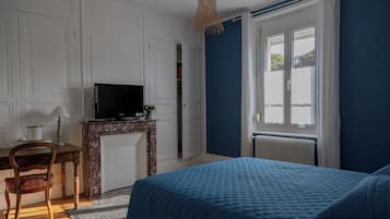 A bedroom with a bed, a desk, a television, and a window.