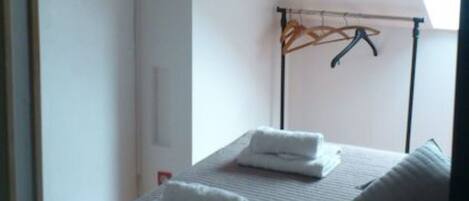 A bedroom with a bed, a TV mounted on the wall, and a window providing natural light.