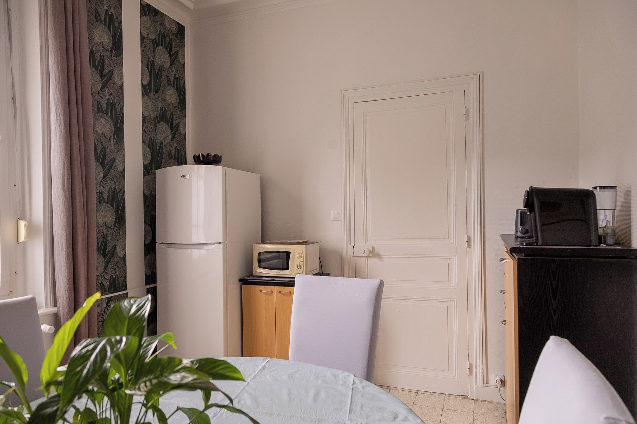 A hotel room with a bed, a desk with a computer, a refrigerator, a microwave, and a coffee maker.