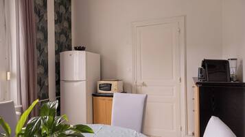 A hotel room with a bed, a desk with a computer, a refrigerator, a microwave, and a coffee maker.