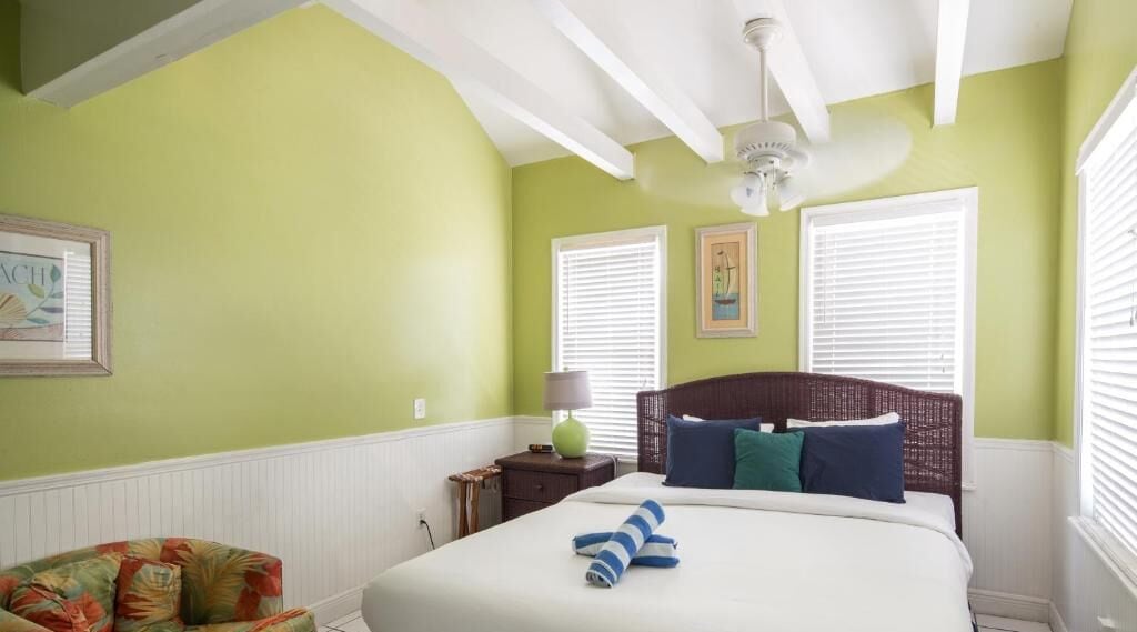 A bedroom with a bed, a nightstand, a lamp, and a chair.