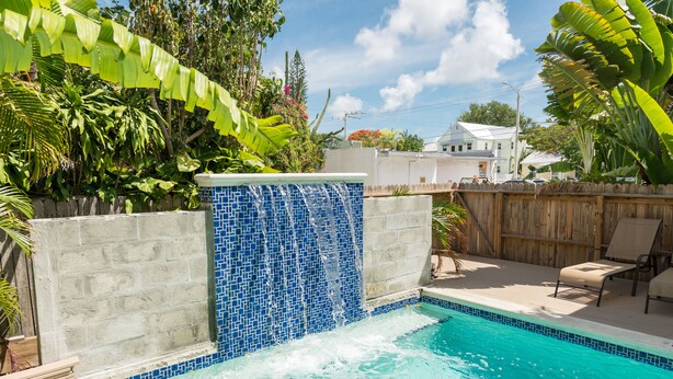A swimming pool with a blue mosaic wall and a waterfall feature.