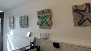 A room with a wooden wall decor featuring starfish and a small shelf with a basket.