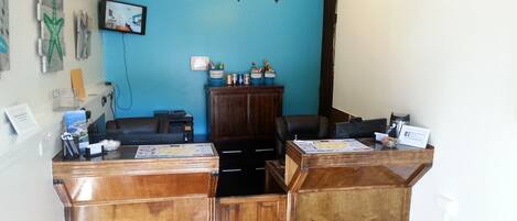 A reception area with a blue wall, wooden reception desks, a chandelier, and artwork.