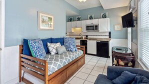 A compact living space with a sofa bed, kitchenette, and a dining area.