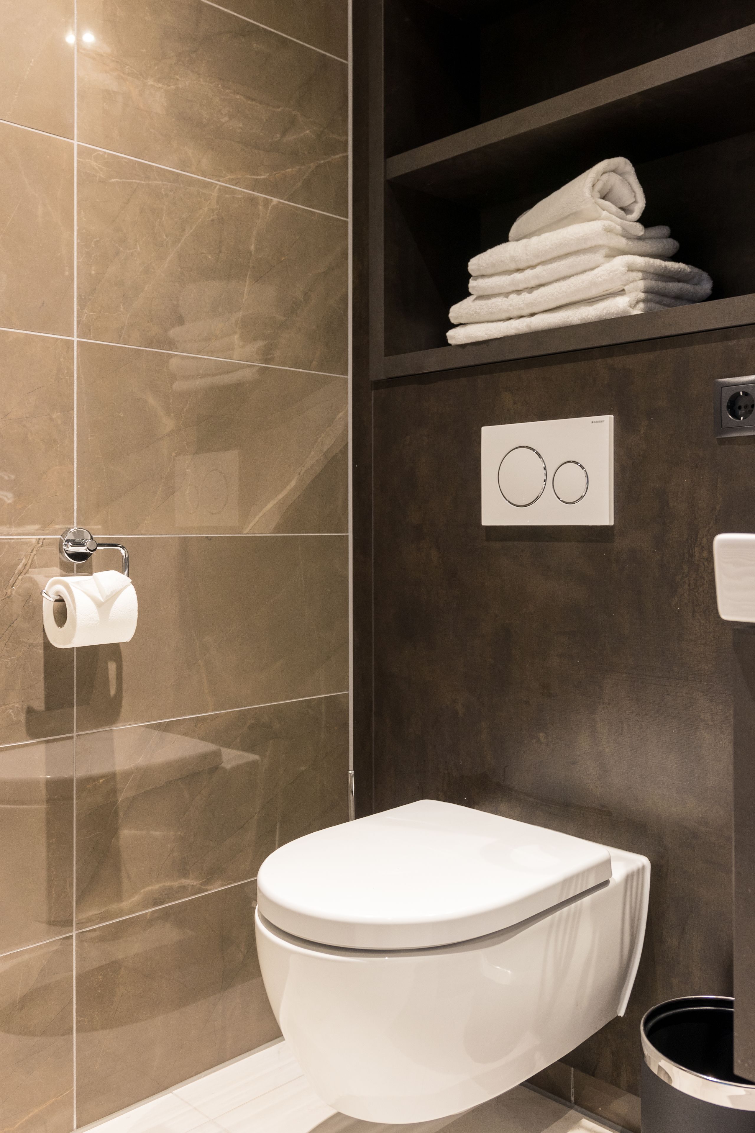 Un baño moderno con inodoro, toallero y dispensador de papel higiénico.