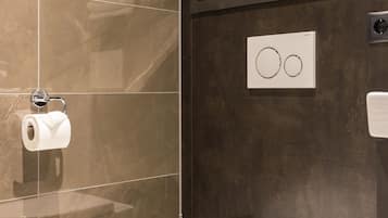 Un baño moderno con inodoro, toallero y dispensador de papel higiénico.