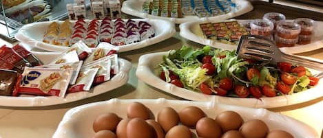 A buffet spread with various food items including eggs, salads, and packaged snacks.