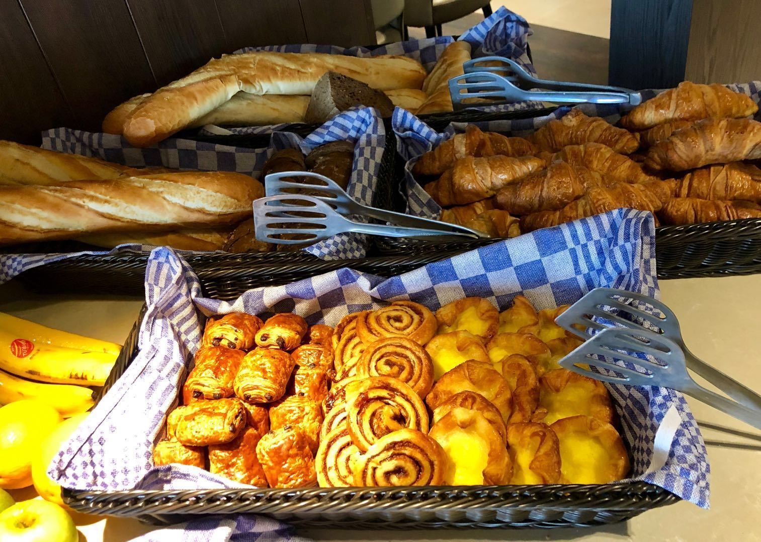 Un buffet proposant une variété de produits de boulangerie, notamment du pain, des croissants et des viennoiseries.