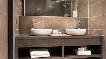 A modern bathroom with two sinks, a mirror, and a towel rack.