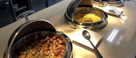 Montaje de bufé con diversos platos, incluyendo albóndigas, arroz y sopa.