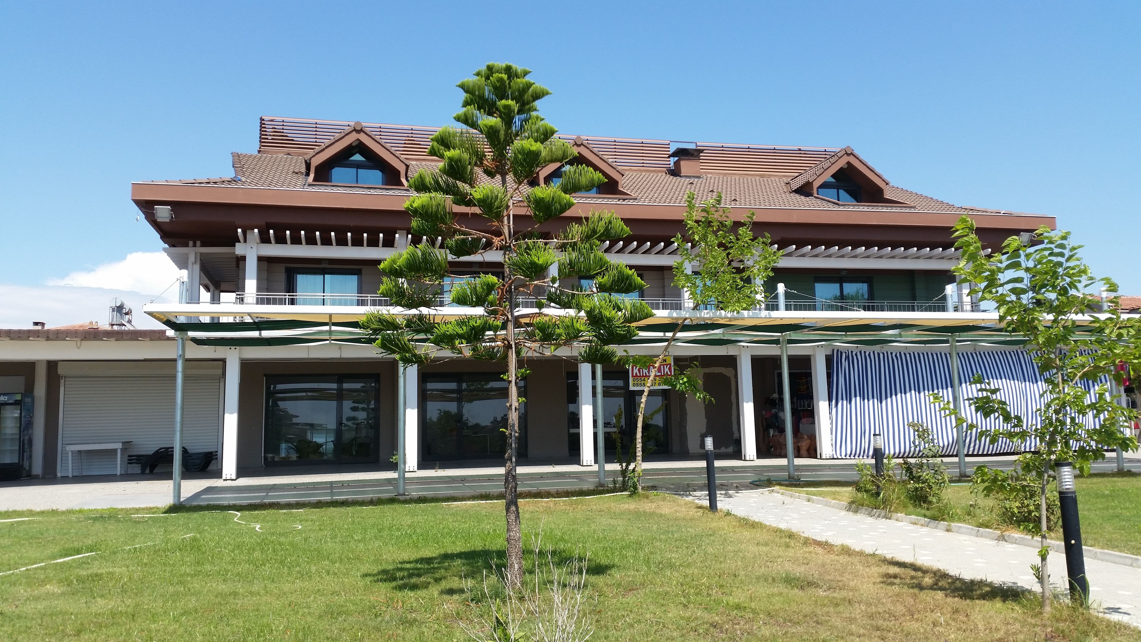 Une maison moderne à deux étages, dotée d’un toit en pente, de grandes fenêtres et d’un porche abrité.