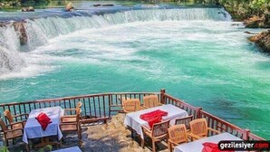Un restaurant avec une terrasse offrant une vue sur une cascade.
