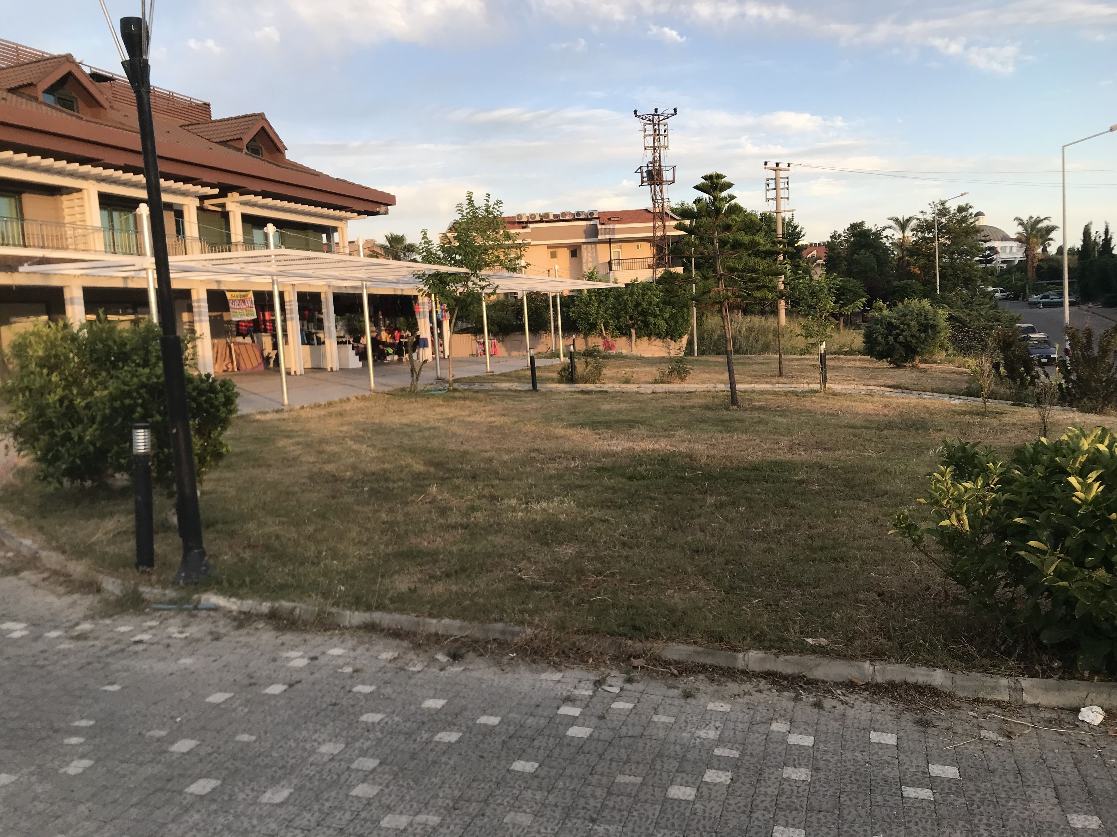 Zona residencial con un sendero pavimentado, un césped y un edificio con techo de tejas.