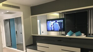 Une chambre à coucher comprenant un lit, un téléviseur fixé à une commode, un miroir et une armoire.