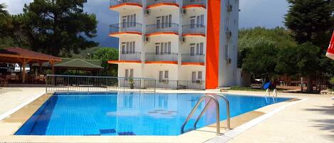 Una piscina con un edificio de varios pisos al fondo.