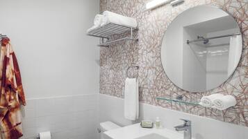 Un baño con lavamanos blanco, espejo, toallero y pared con diseño.