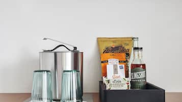 A kitchen setup with a kettle, two glasses, a bag of snacks, and a bottle of Slingshot coffee.