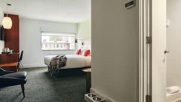 Ein Hotelzimmer mit Bett, Schreibtisch, Stuhl, Fenster und Badezimmer.