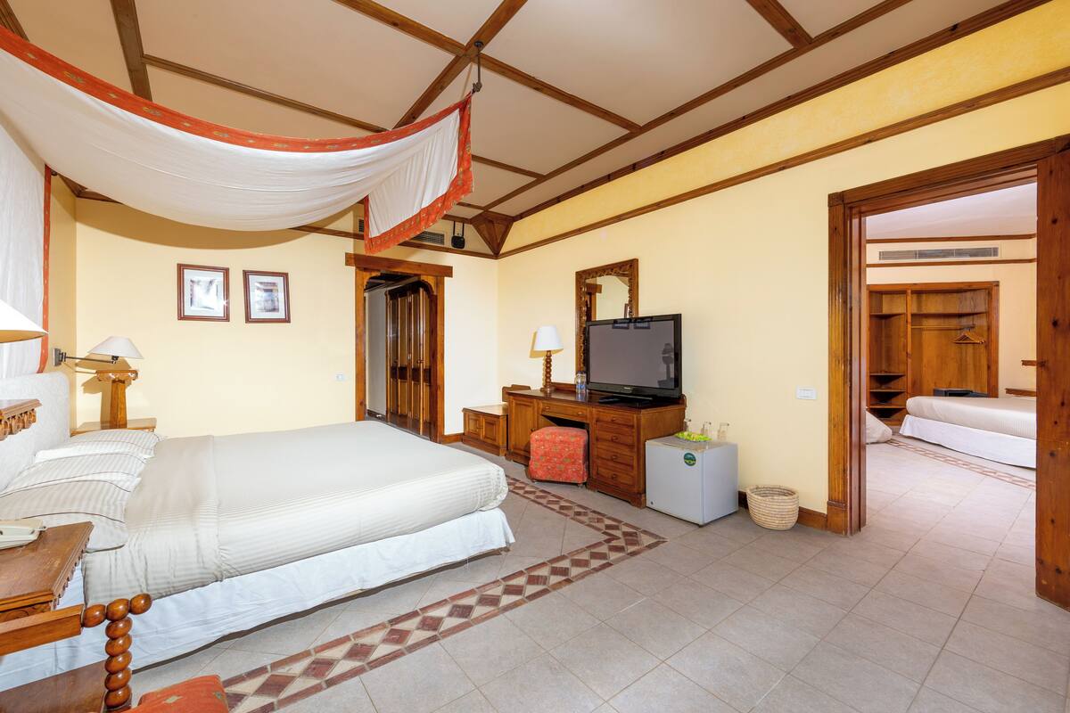 Ein Hotelzimmer mit Bett, Fernseher, Schreibtisch und Kleiderschrank.