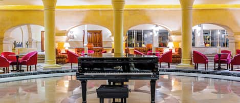 A grand piano in a spacious lobby with high ceilings and classical columns.
