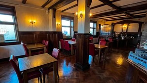 Een restaurant met houten vloeren, rode en witte zitplaatsen en zichtbare balken in het plafond.