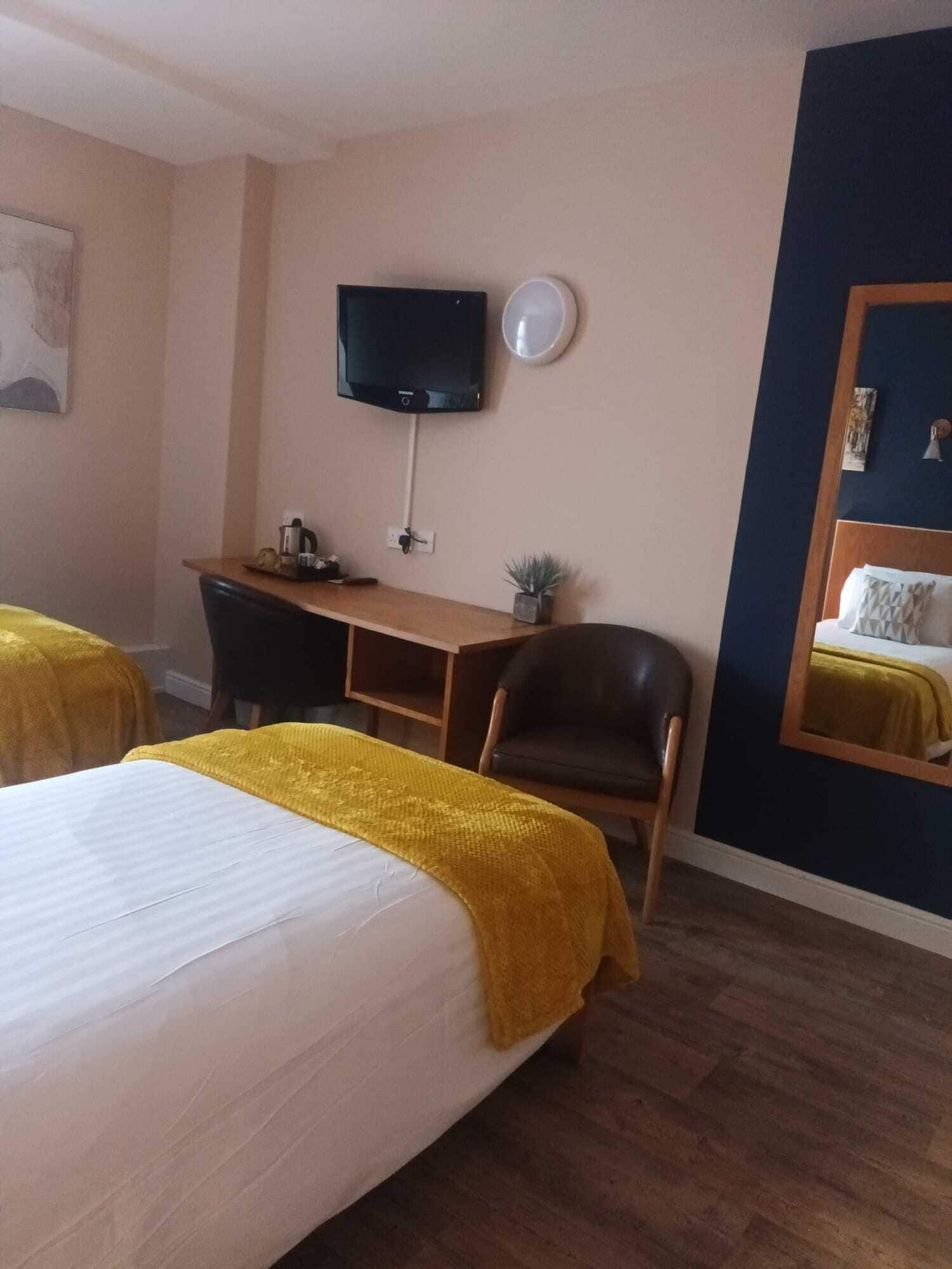 Ett hotellrum med två sängar, ett skrivbord med en stol, en tv och en liten krukväxt.