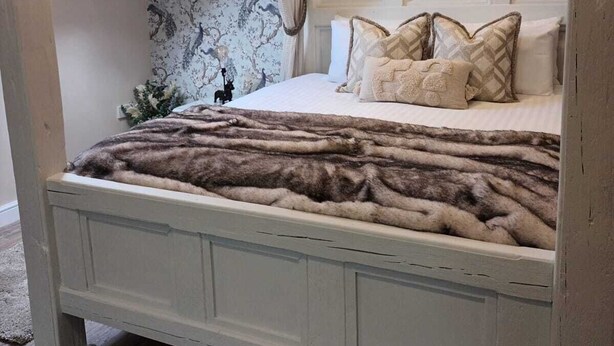Een slaapkamer met dakraam, een decoratieve krans en een behang met patroon.