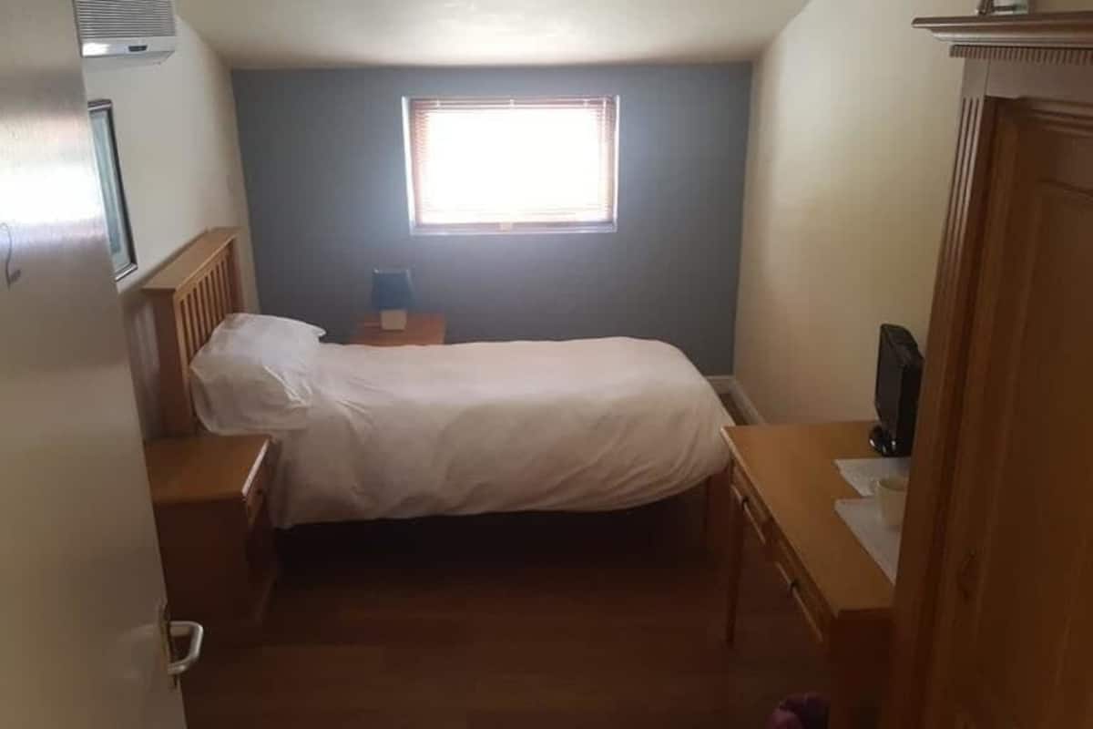 A bedroom with a bed, bedside tables, a window, and a TV.