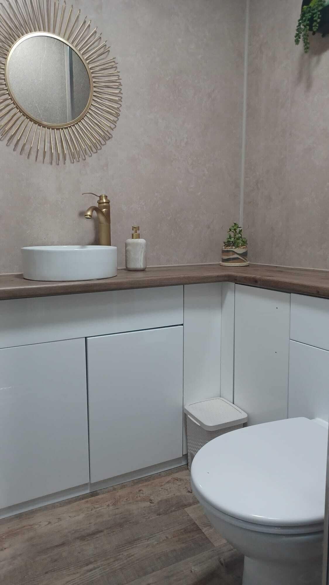 A bathroom with a round mirror, a sink, and a toilet.