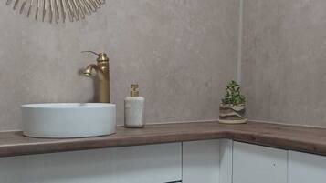 A bathroom with a round mirror, a sink, and a toilet.