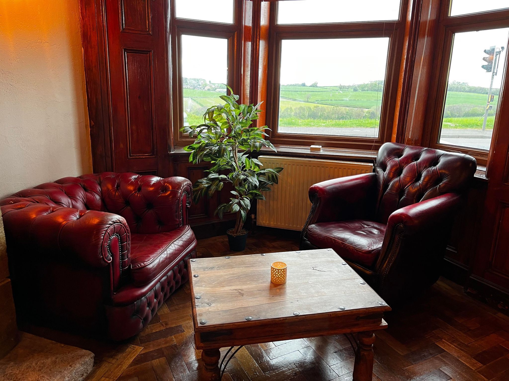 A room with two leather armchairs, a wooden coffee table, and a potted plant.