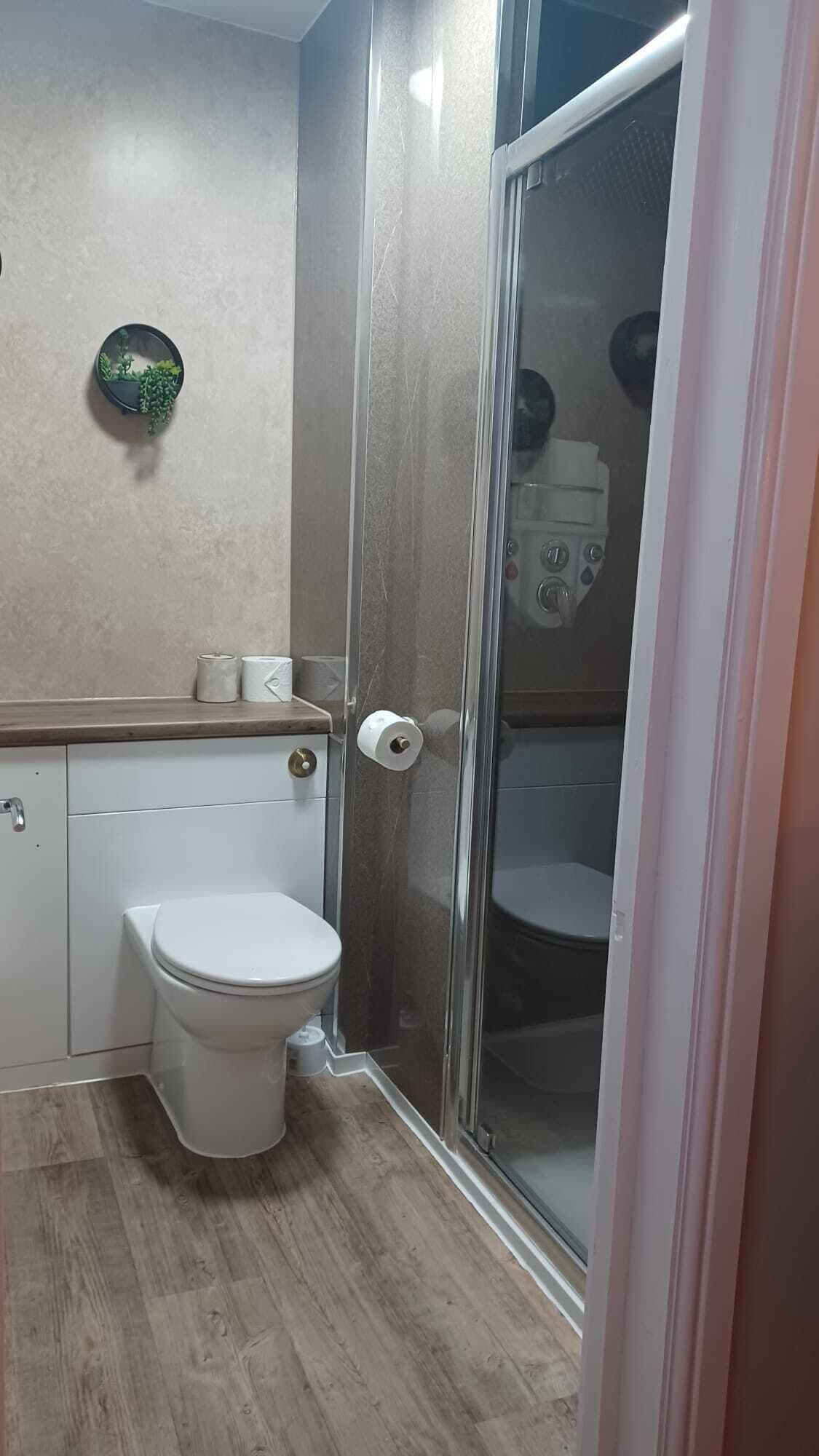 Une salle de bain comprenant des toilettes, une douche avec une porte en verre et un porte-serviettes.