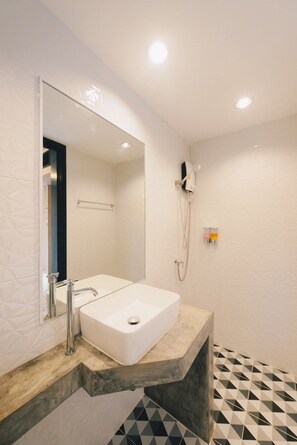 A modern bathroom with a white sink, a mirror, and a shower. - Kipbox Hotel Trang (Trang)