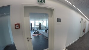 A hallway with a door leading to a fitness area. - Terminal Hotel One (Sindelfingen)