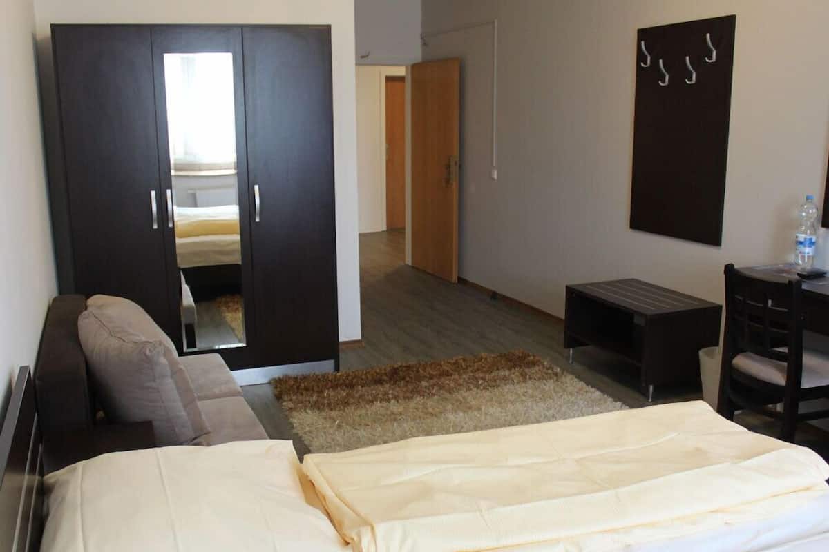 A hotel room with a bed, a sofa, a desk, and a wardrobe.